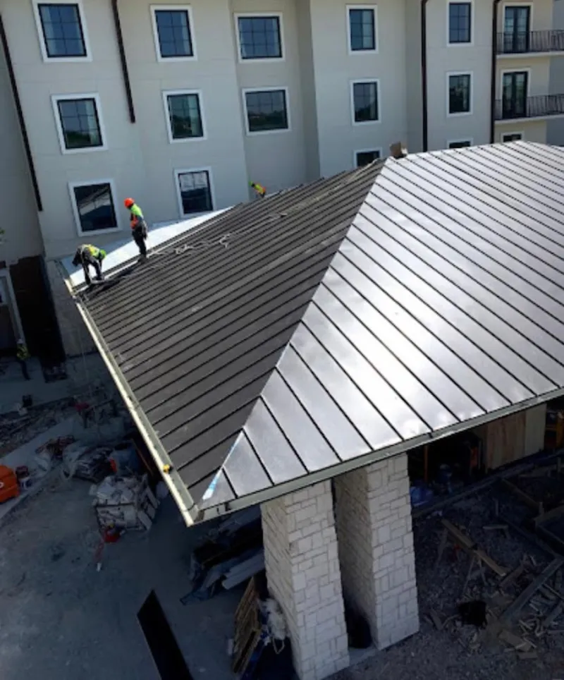 Crew installing standing seam metal roof panels on a commercial project in Leon Valley
